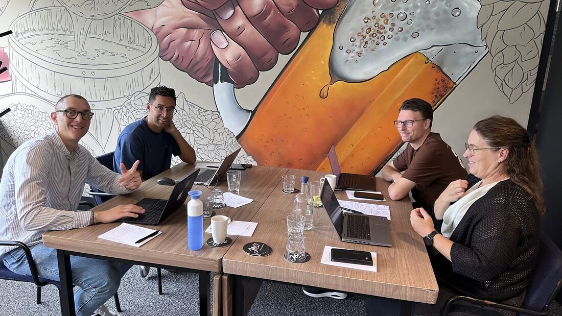 A group of delegates works at a table beneath a large wall mural.