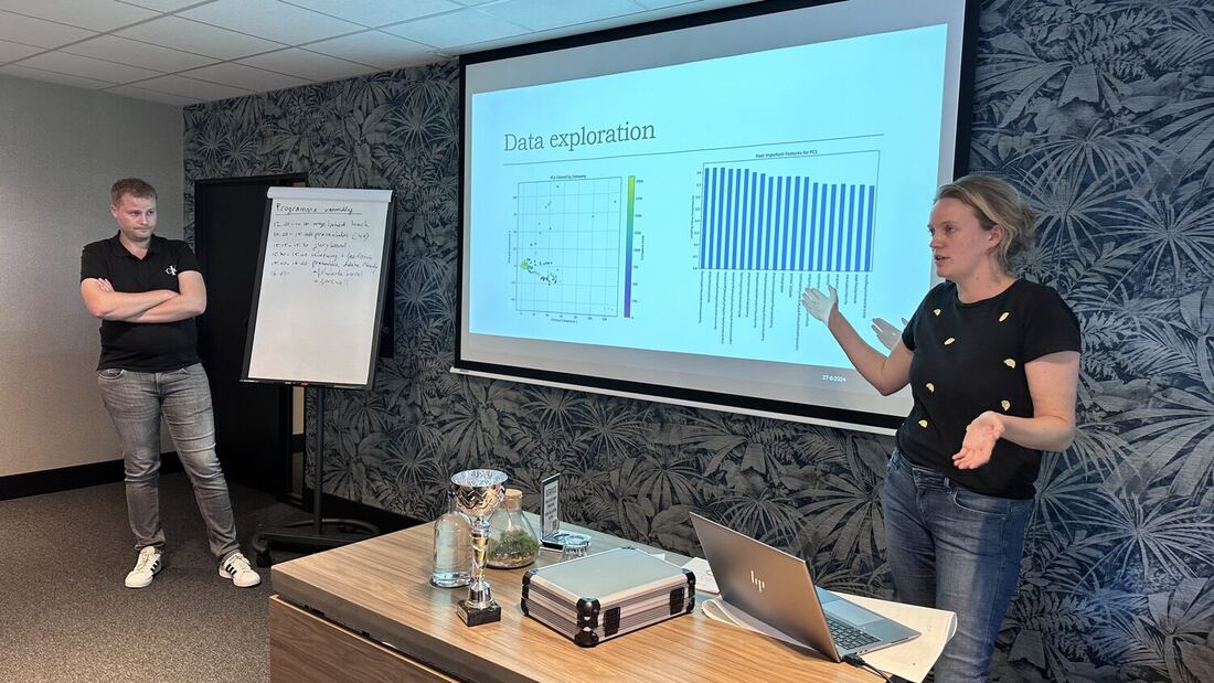 A student points at a data exploration chart on screen while a teammate stands alongside.