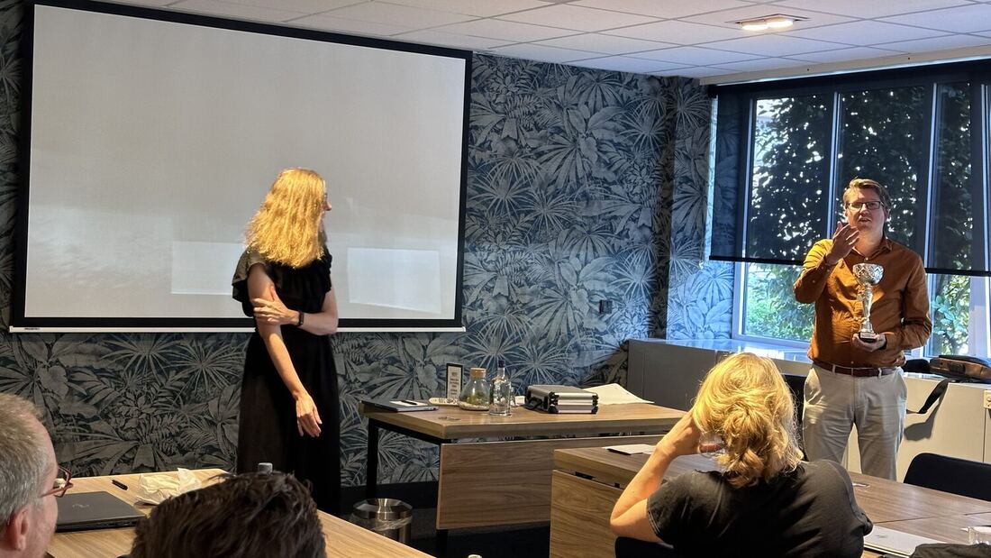 The room seen from the back during a presentation, with speakers at either side of the screen.