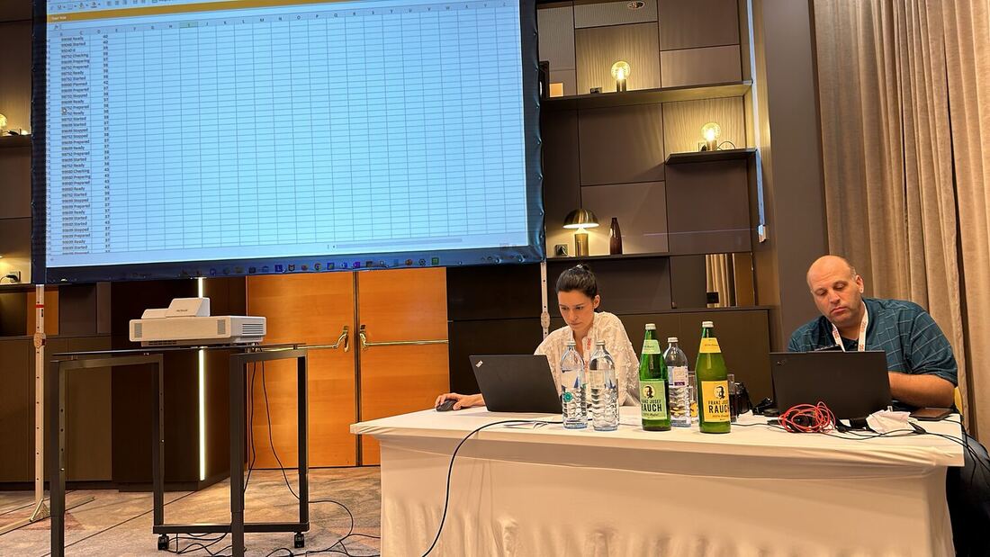A hands-on session with a spreadsheet of machine state events projected on the screen while two instructors work from laptops at a table.