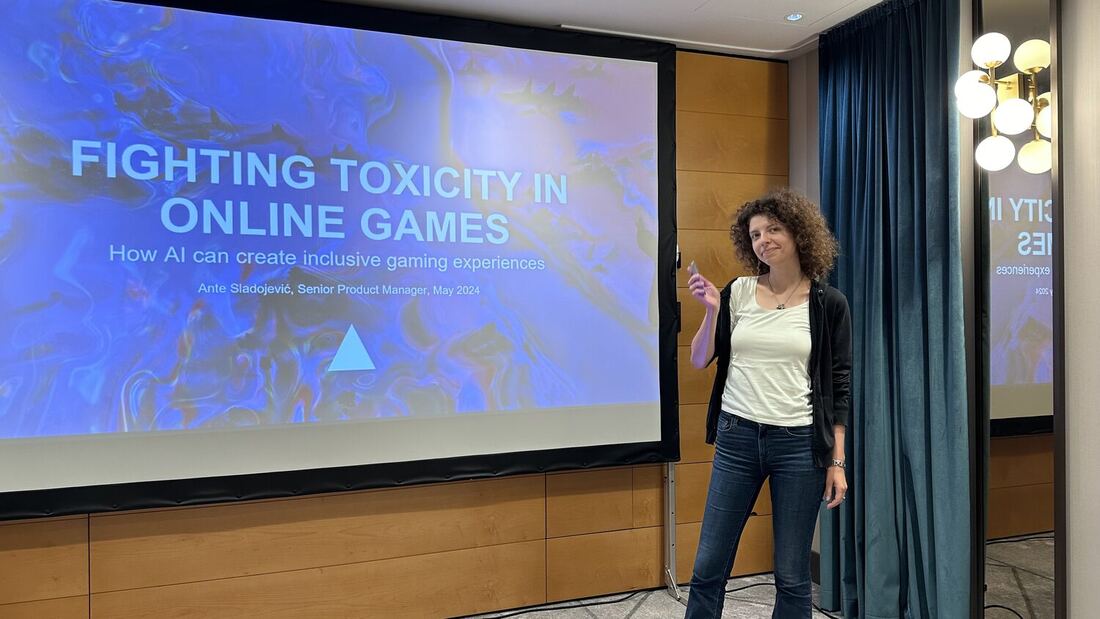 A speaker stands beside her opening slide, Fighting Toxicity in Online Games, in an empty session room the night before the conference.