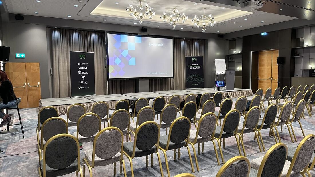 The main hall set out with rows of gold banquet chairs before the doors open, DSC DACH roll-up banners either side of the stage and a Marriott Vienna lectern at the right.