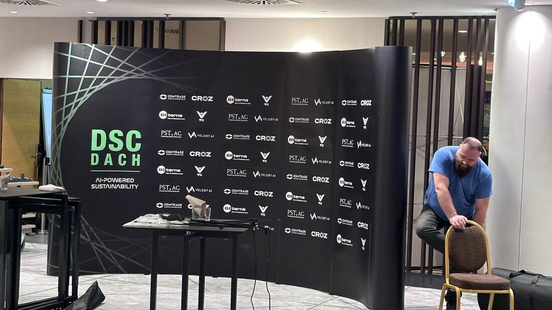 The DSC DACH sponsor wall being put up at the venue, logos for Comtrade, CROZ, BE-terna, VIS, PST.AG and Velebit AI repeated across it.