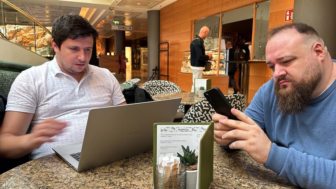 Two organisers work from a laptop and a phone in the hotel lobby the day before the conference opened.