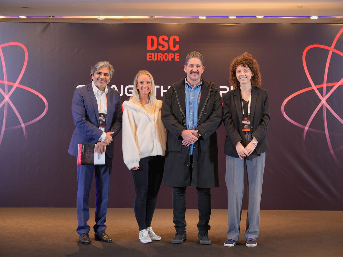 Four people stand together in front of the DSC Europe photo wall
