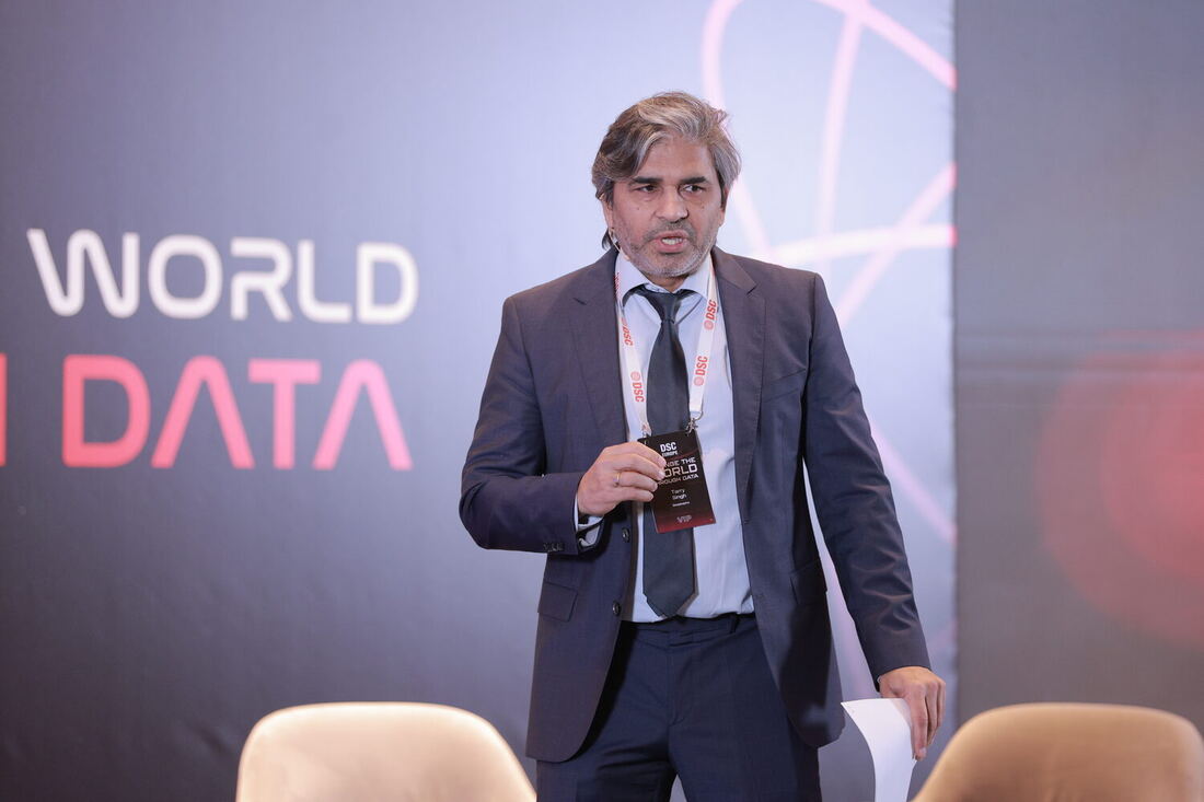 The host addresses the main hall with a handheld microphone in front of the Change the world through data backdrop