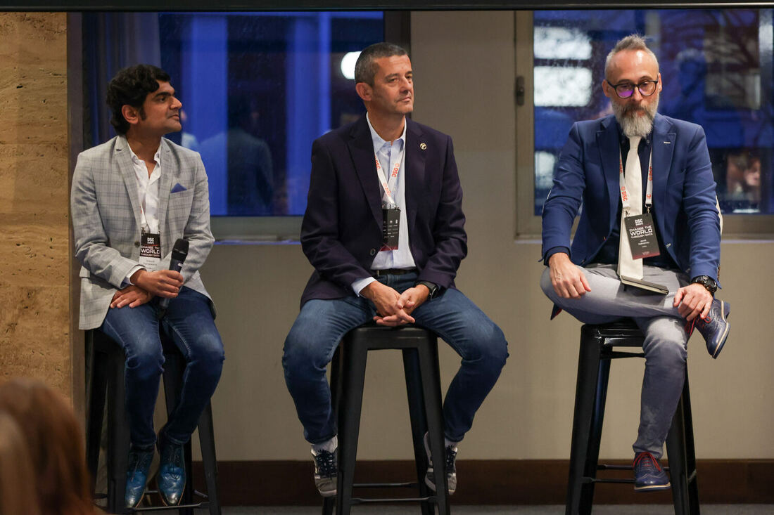 Three panellists seated on stools on a small stage