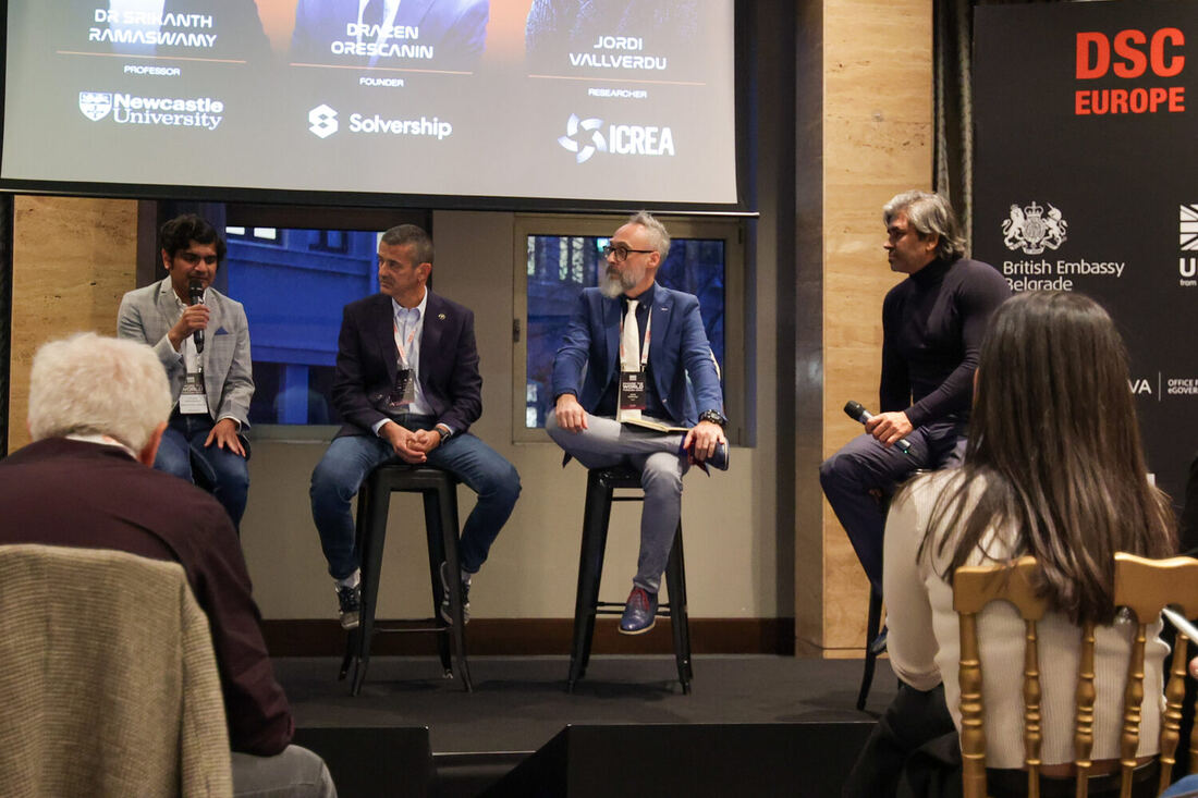 A panel on stage seen from the side of the room