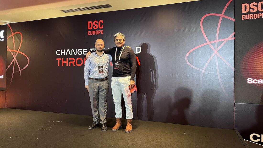 Two delegates in front of the DSC Europe backdrop