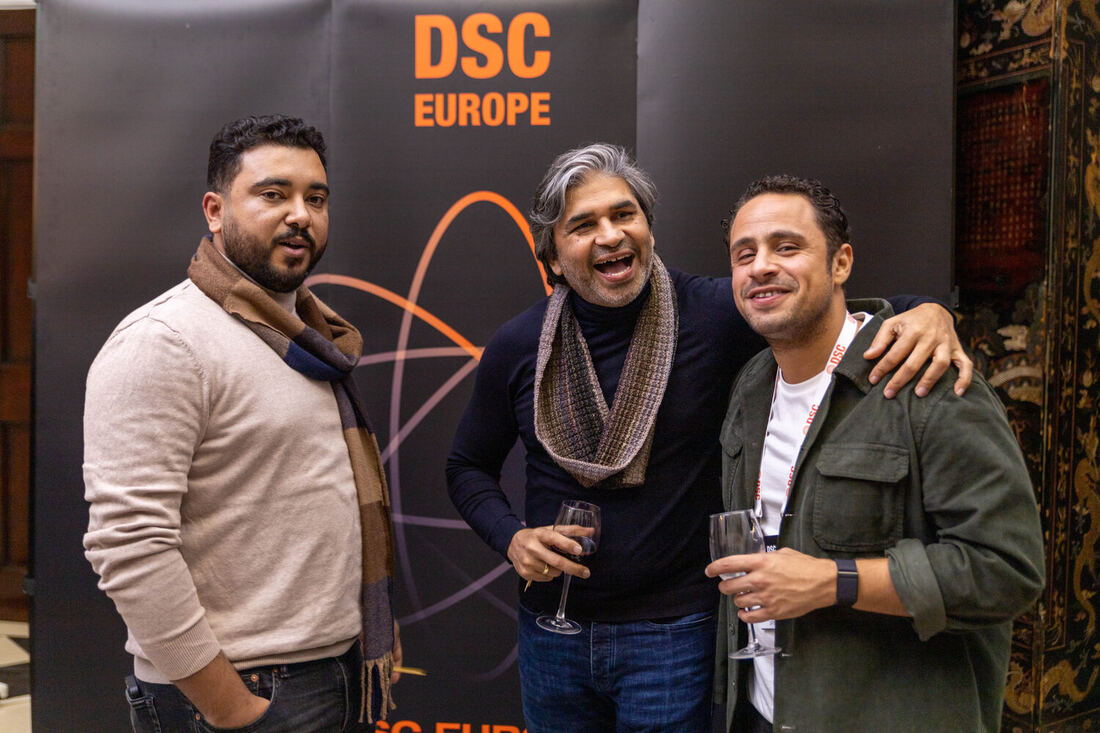 Three delegates at the DSC Europe wall during an evening reception