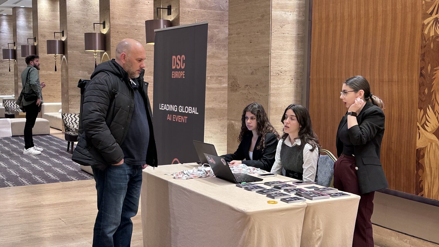 Registration desk with three staff and a table of badges beside a DSC Europe pull-up banner reading Leading Global AI Event.