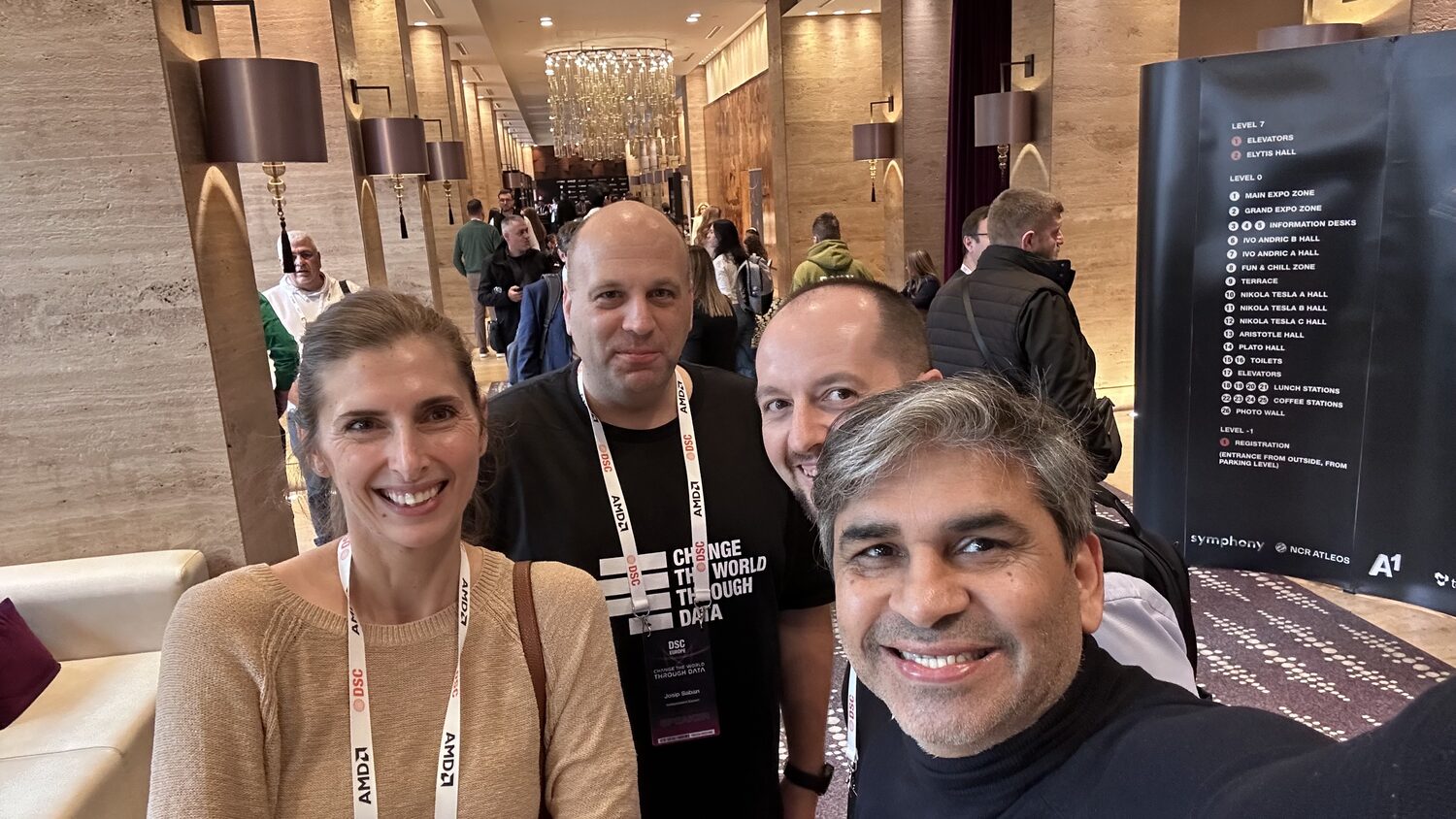 Four delegates in the venue corridor beside the DSC Europe floor directory listing Elytis, Nikola Tesla, Ivo Andric, Aristotle and Plato halls.