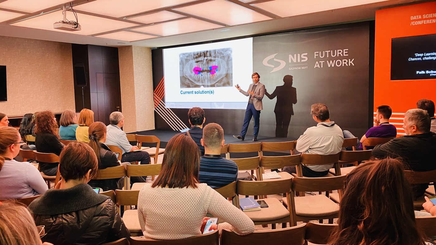 The side hall session, a smaller room under NIS Future at Work branding, delegates seated at tables facing the screen.