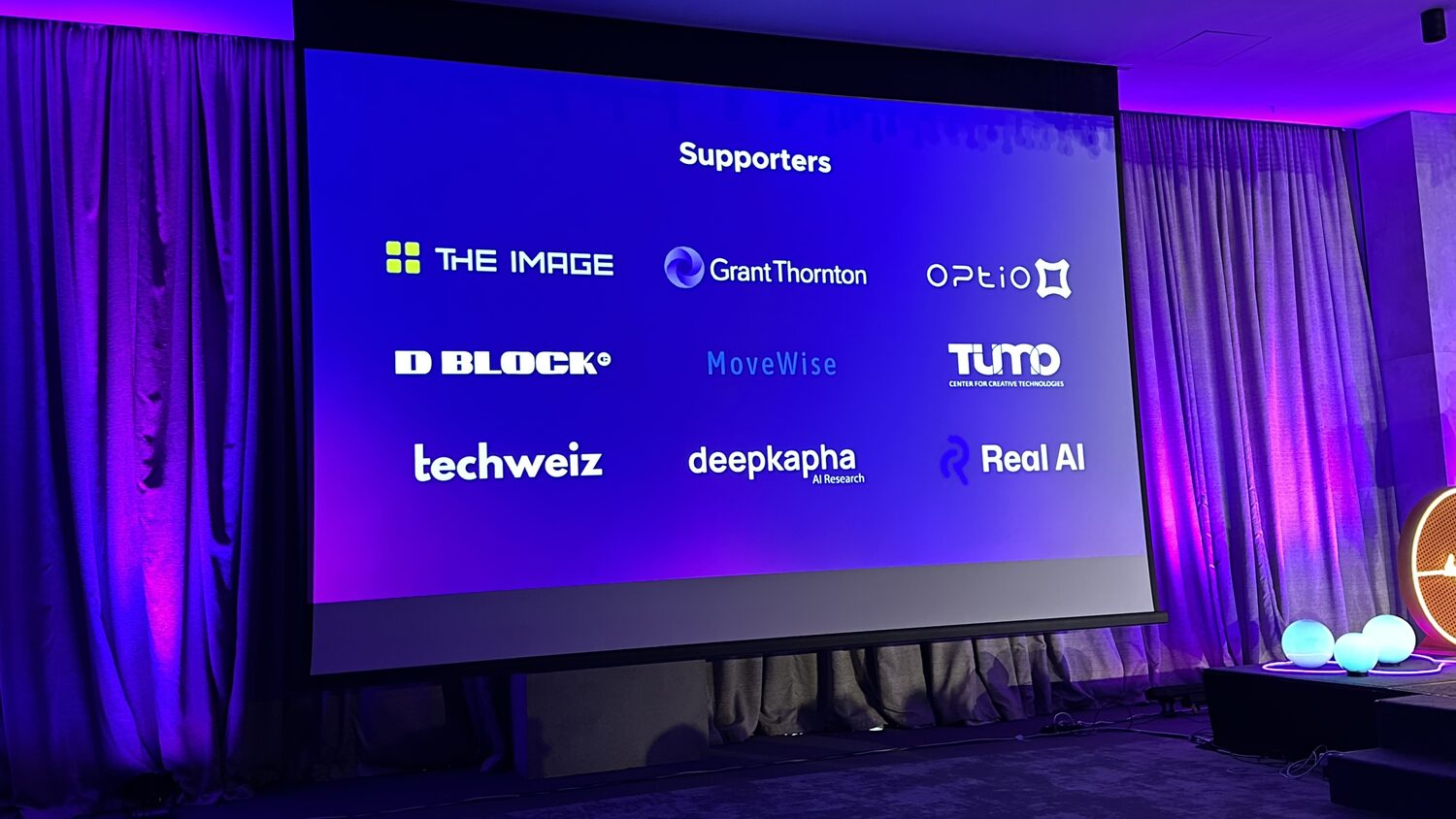 Supporters slide on the main screen, nine logos in three rows with deepkapha AI Research and Real AI along the bottom