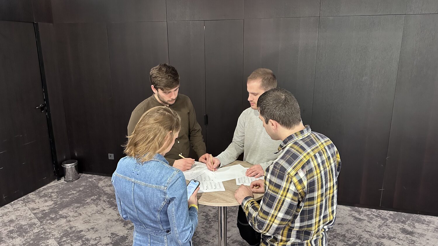 Four participants standing around a round table, writing on the canvas handout