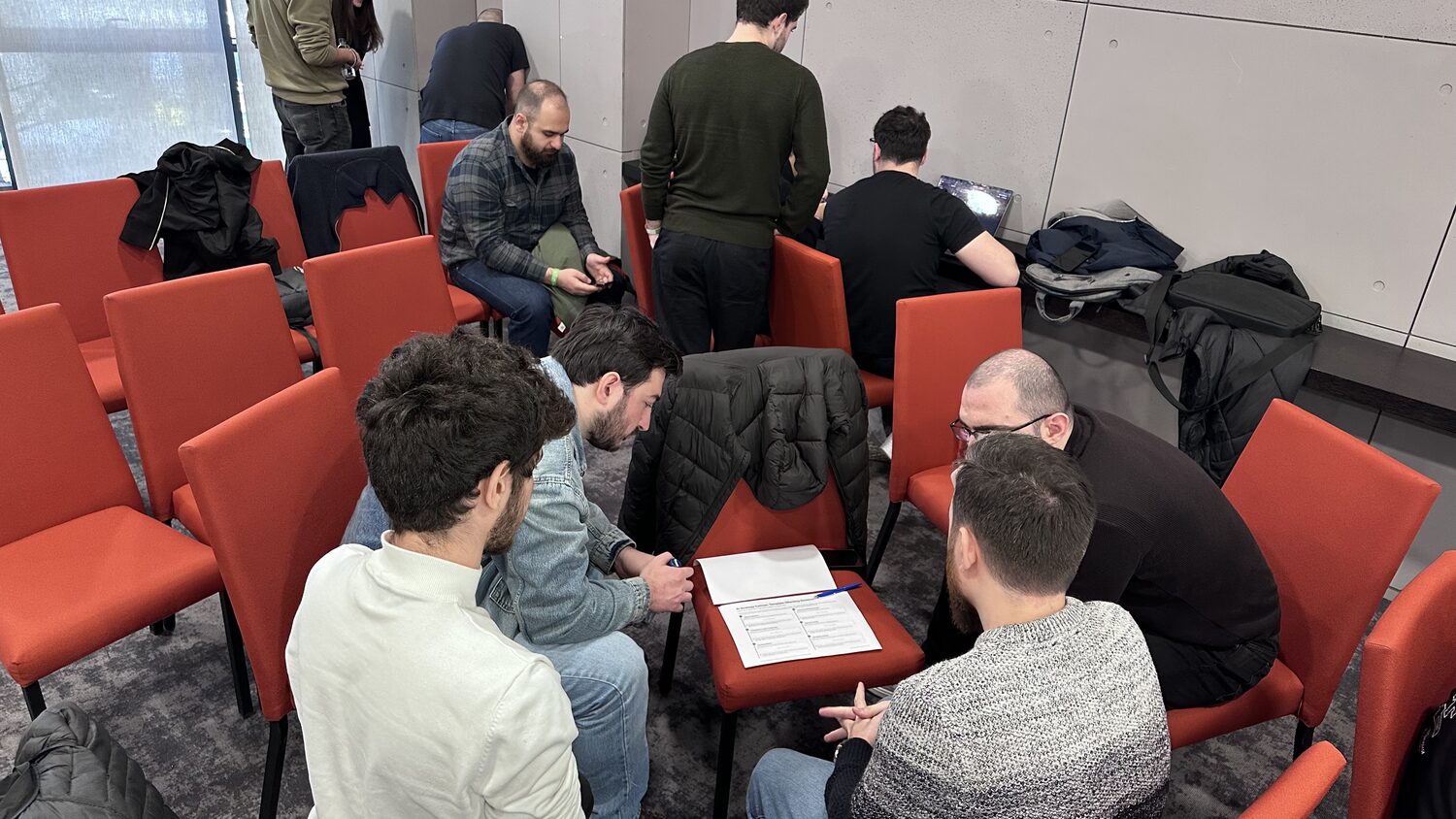 A cluster of participants in red chairs working through the canvas together