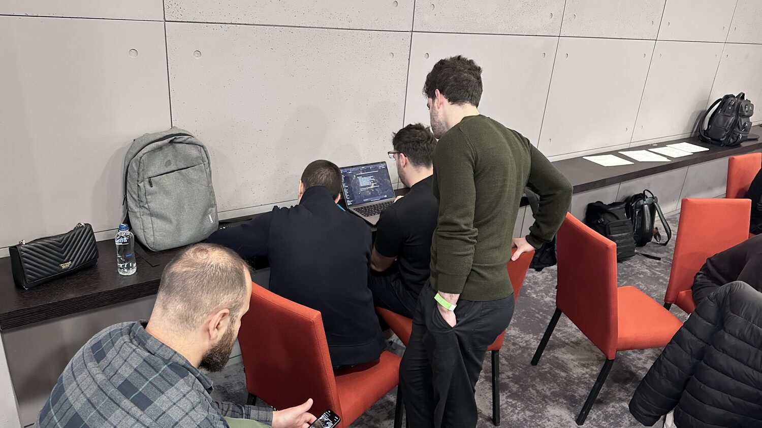 Participants gathered around a laptop at the back of the workshop room