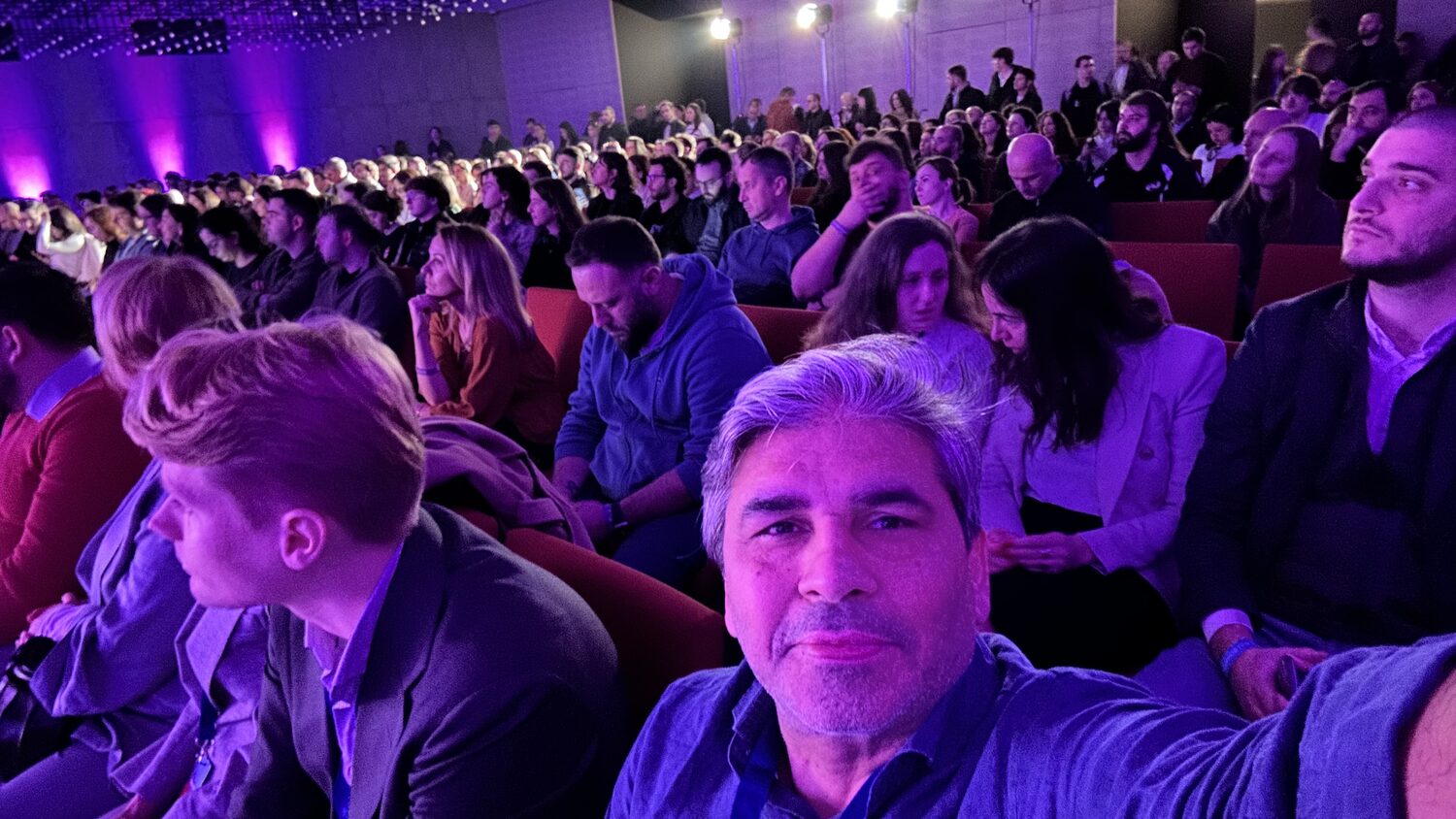 The main hall audience seen from a middle row, every seat taken