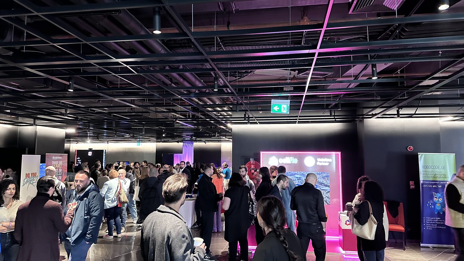Conference foyer with sponsor stands, roll-up banners and delegates at the coffee break