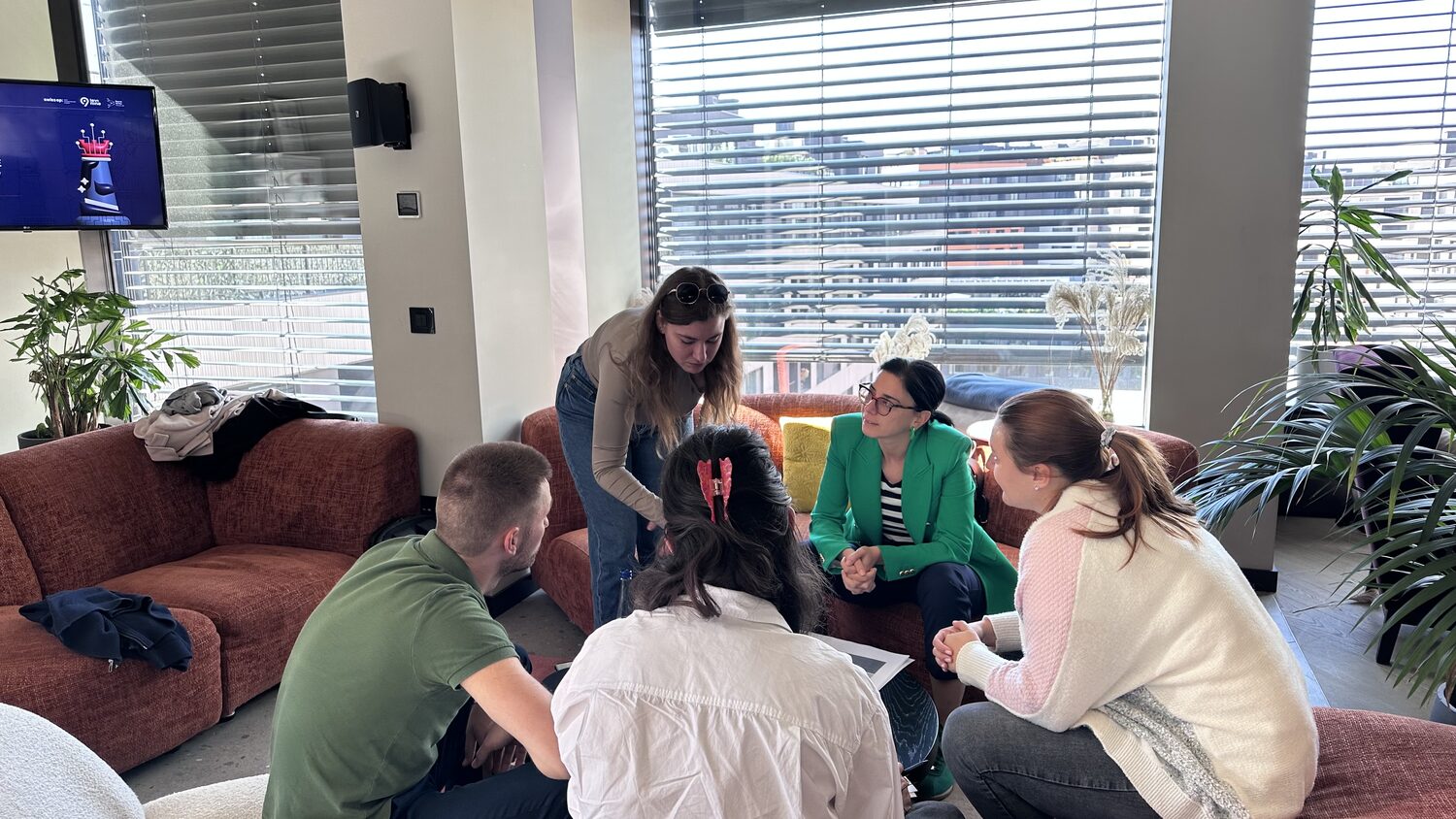 Breakout group on sofas beside a window, papers and a coffee cup on the low table between them.