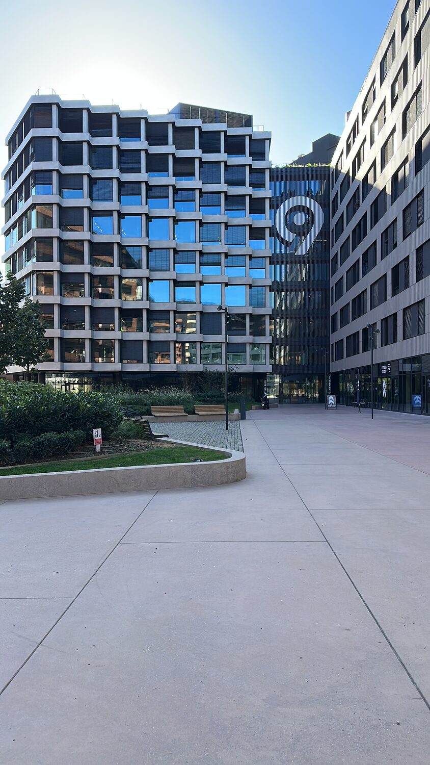 Office building in Novi Beograd with a large 9 mark on its glass facade, seen from an empty plaza.