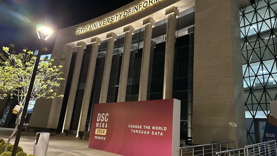 Egypt University of Informatics at night with the DSC MENA 2024 Change the World Through Data hoarding at the entrance.