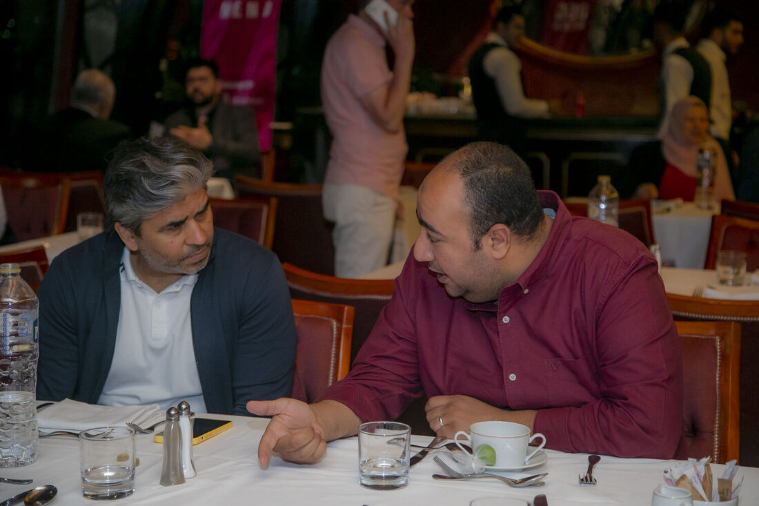 Tarry Singh in conversation with another guest at the conference function, a pink DSC banner behind them.