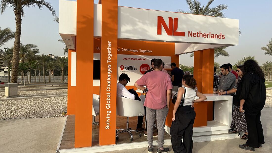 Visitors at the counter of the NL Netherlands pavilion, signage pointing to Orange Corners and Invest in Holland