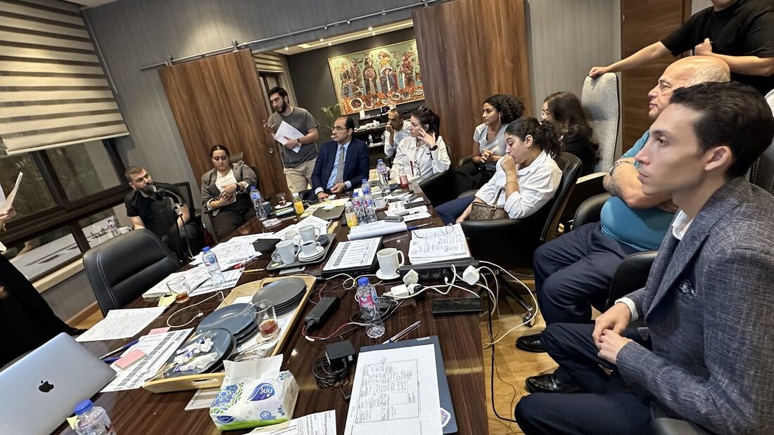 Boardroom table in New Cairo, participants listening while a colleague presents from the far end