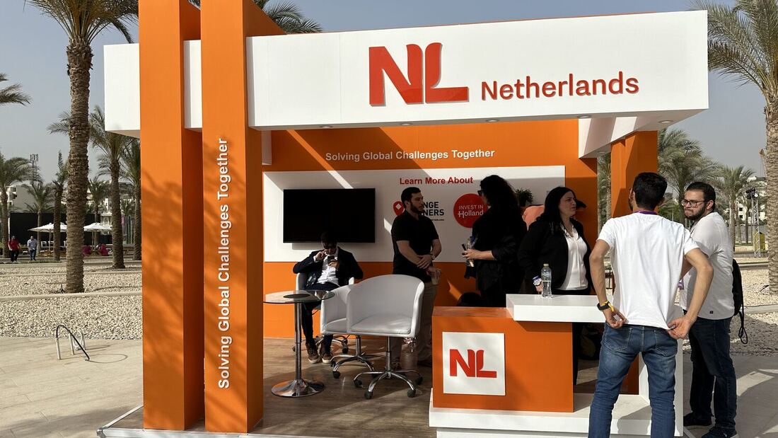The NL Netherlands pavilion in afternoon light, visitors gathered at the open counter