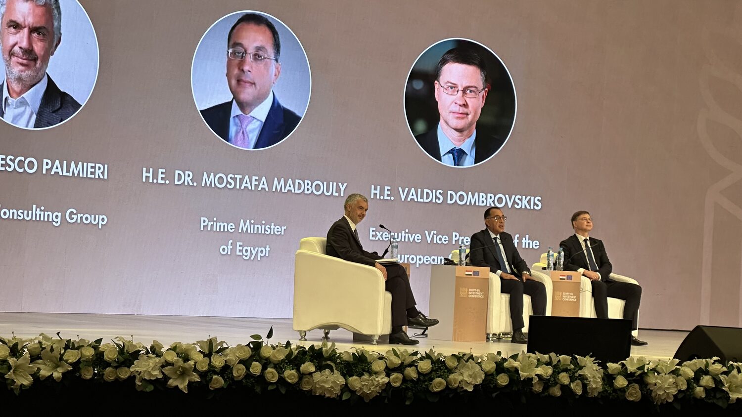 Prime Minister Mostafa Madbouly and Executive Vice President Valdis Dombrovskis seated on stage beneath their names on the conference screen.