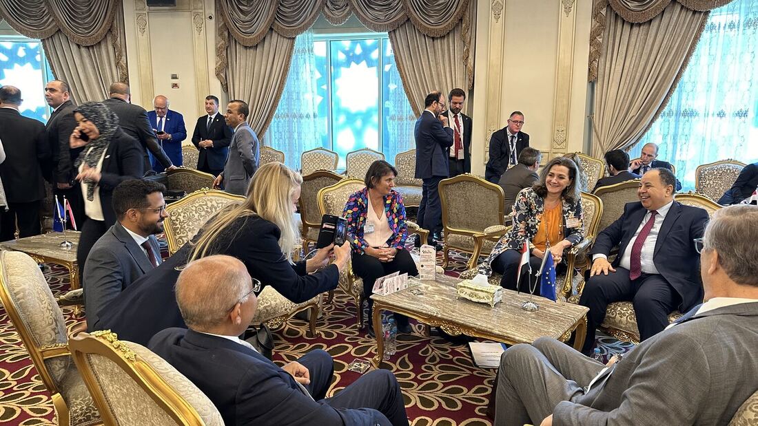 Delegates in conversation around a low table in the lounge, small Egyptian and EU flags set between them.