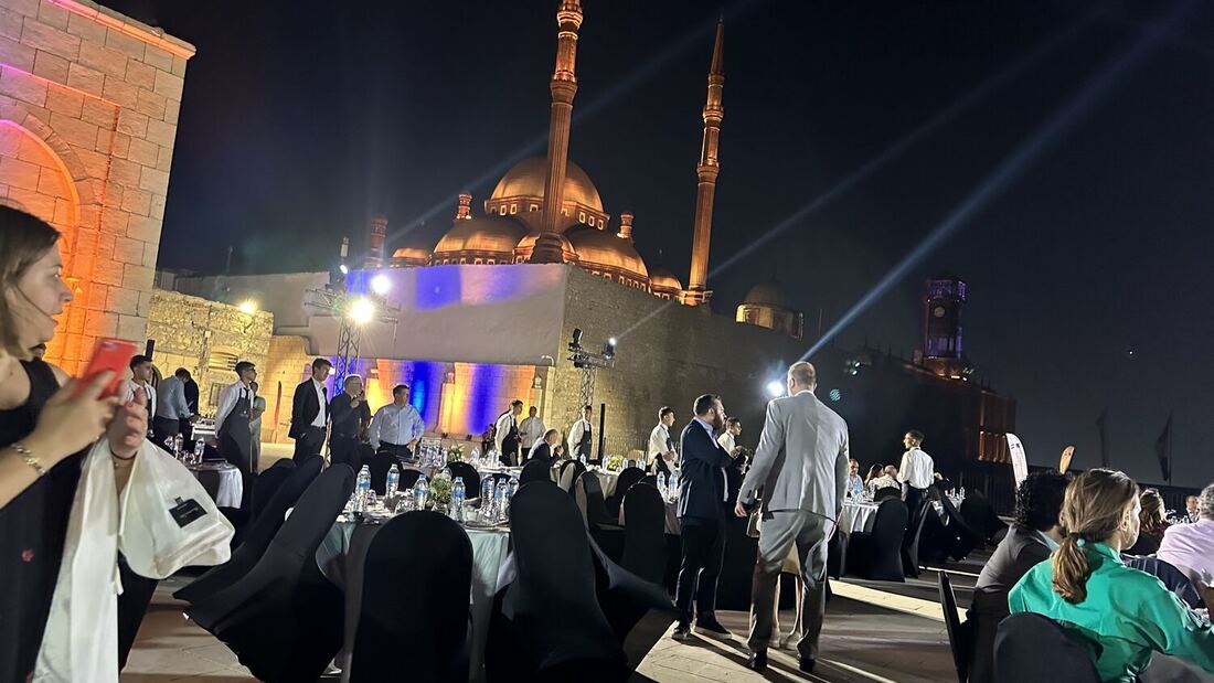 The conference dinner laid out at the Cairo Citadel, guests moving between the tables with the floodlit Mosque of Muhammad Ali behind.