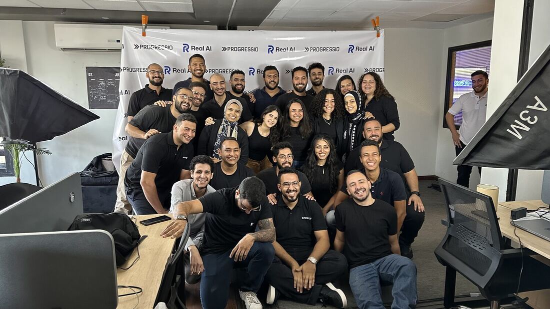 The Progressio team photographed together under a banner carrying the Progressio and Real AI marks.