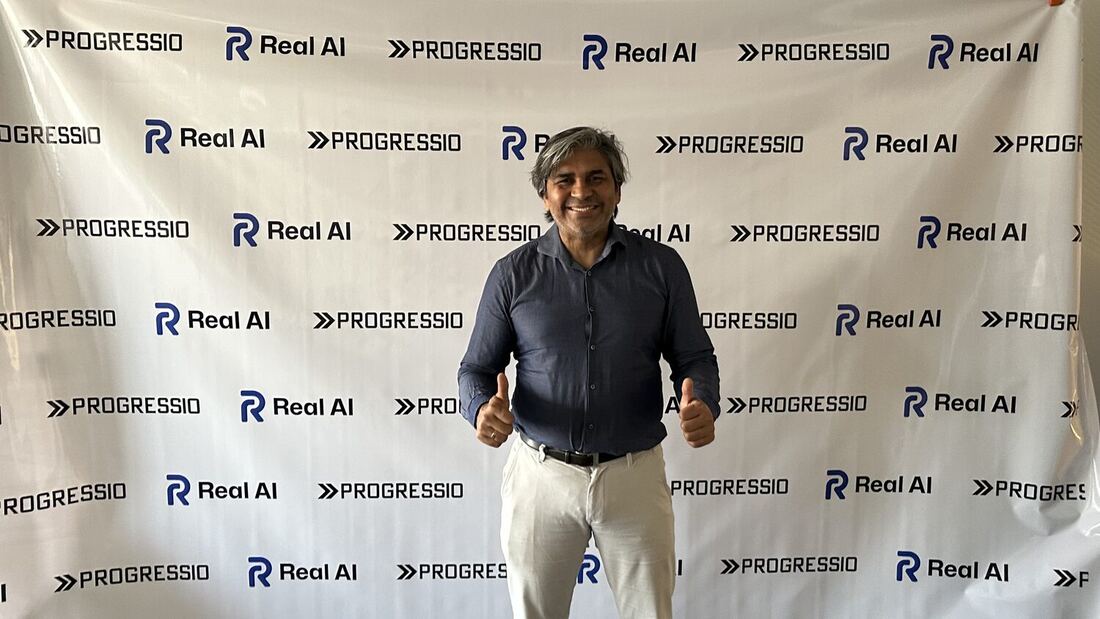 Tarry Singh standing in front of the Progressio and Real AI banner at the Progressio office.