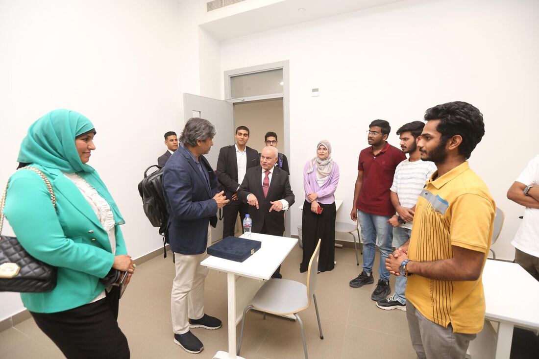 The classroom after the session, a boxed gift on a white table, students and hosts standing in a loose circle.