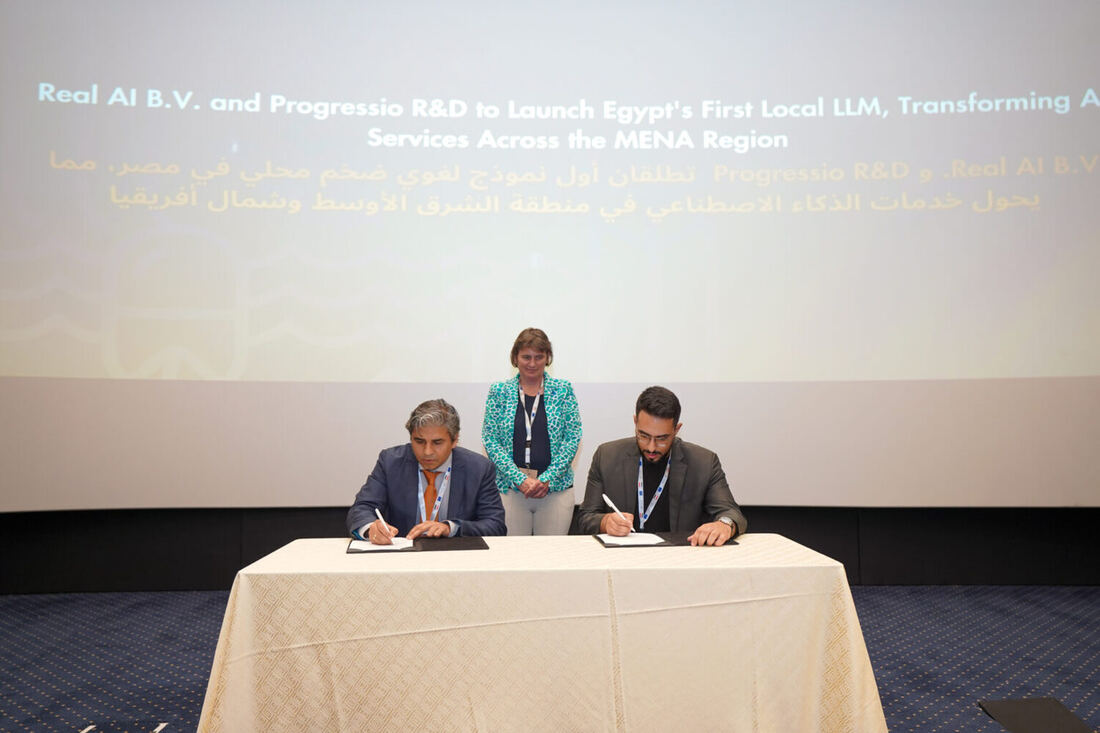Two signatories at a covered table signing documents on the Egypt-EU Investment Conference stage, a witness standing behind them and the announcement slide projected above.