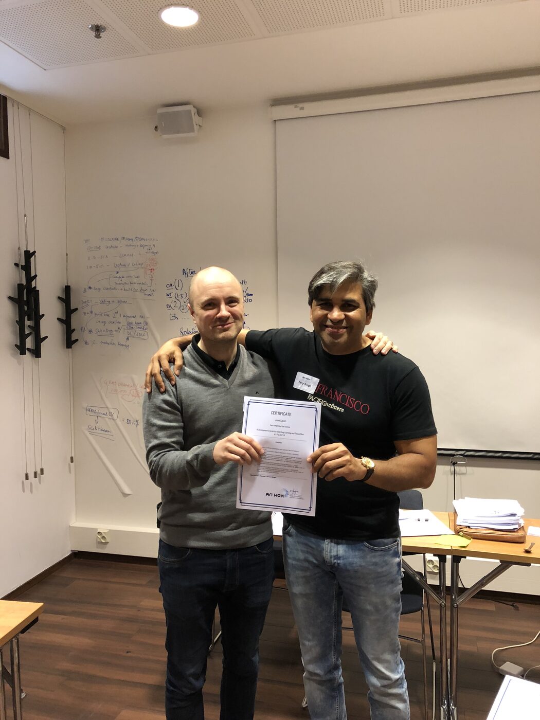 Another certificate handover at the close of the second day, in front of the working whiteboard.