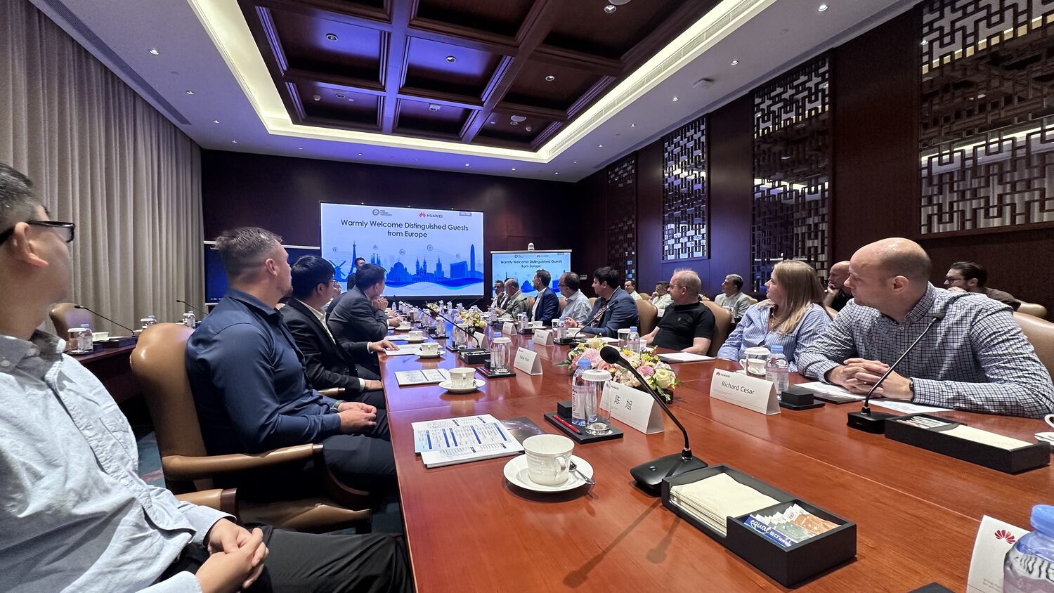 Wide view of the Bantian boardroom during the opening session, welcome screen at the head of the table.