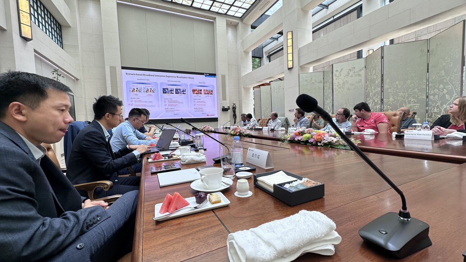 Boardroom in session on 1 July, a Huawei slide on the wall screen and delegates taking notes.