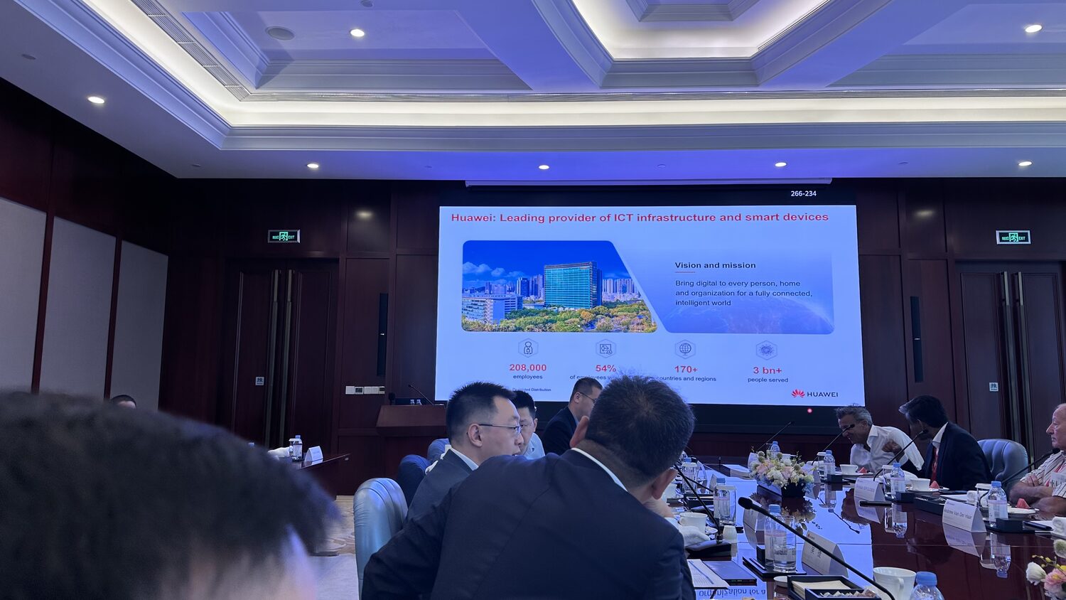A Huawei slide on ICT infrastructure and smart devices on screen, the room seated in front of it.