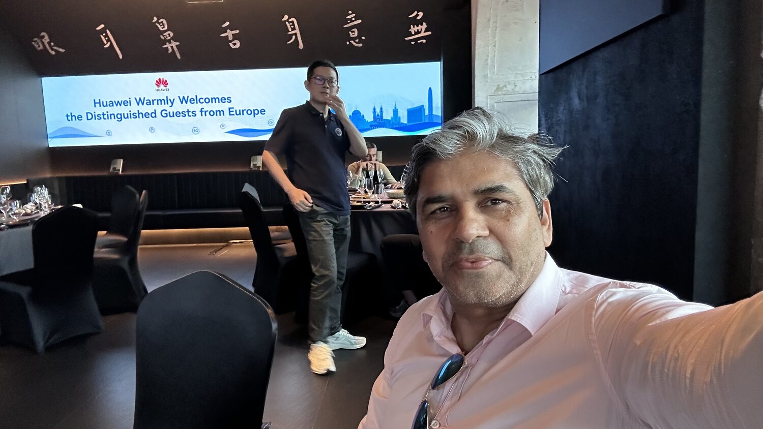 The Shanghai dinner venue on 3 July, Huawei Warmly Welcomes the Distinguished Guests from Europe on a wall-width screen, a host standing beside it.