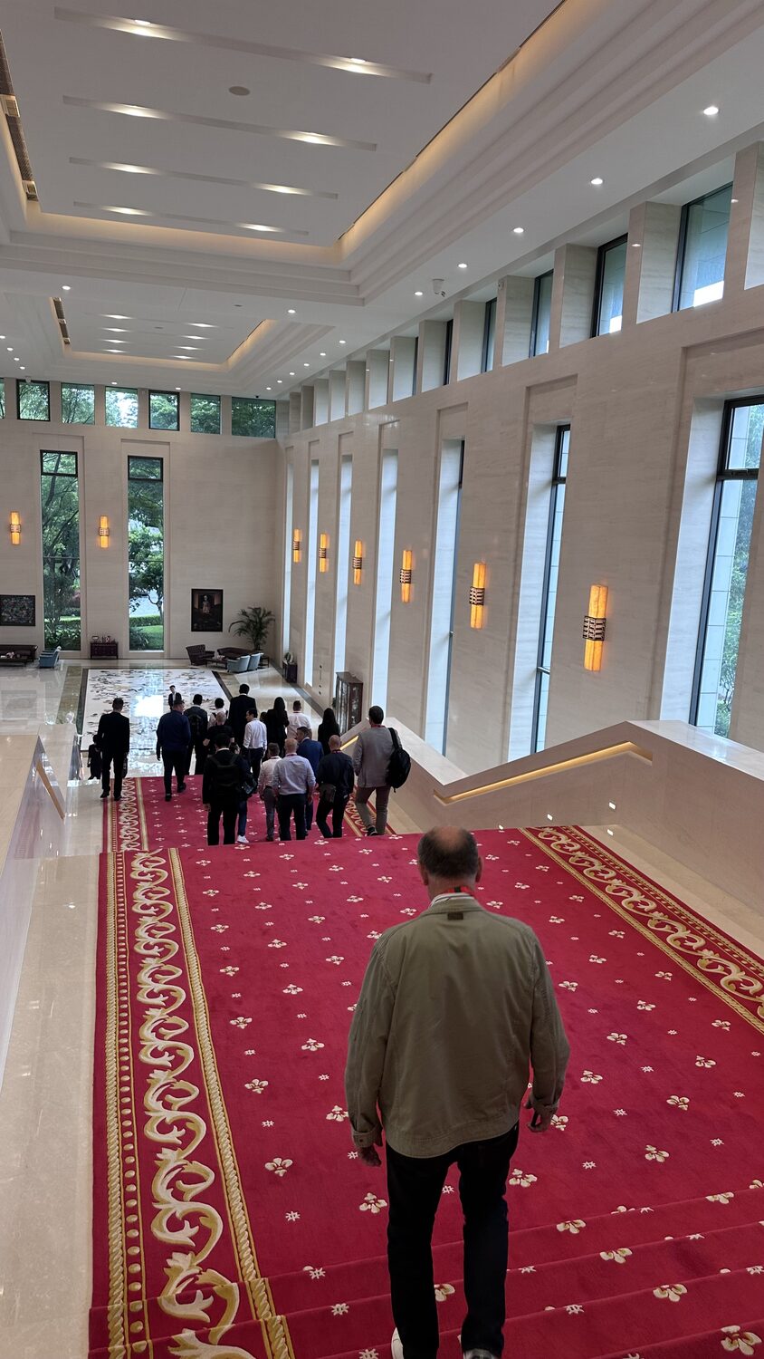 A red-carpeted corridor at the Shenzhen venue, a delegate walking ahead, 30 June.