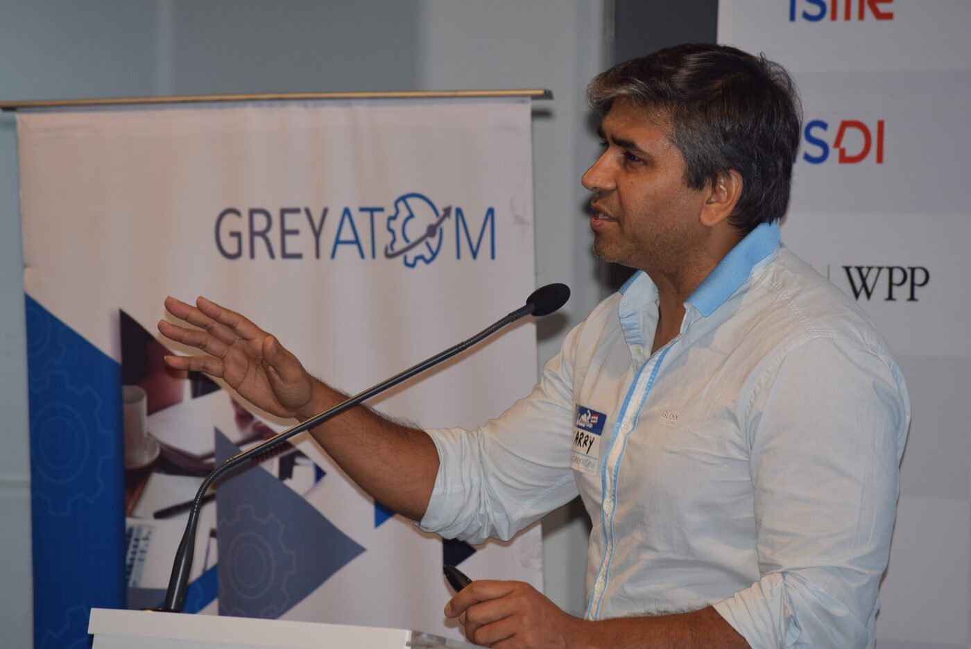 Tarry Singh speaking into a microphone in front of a GreyAtom banner at the DataGiri event in Mumbai.