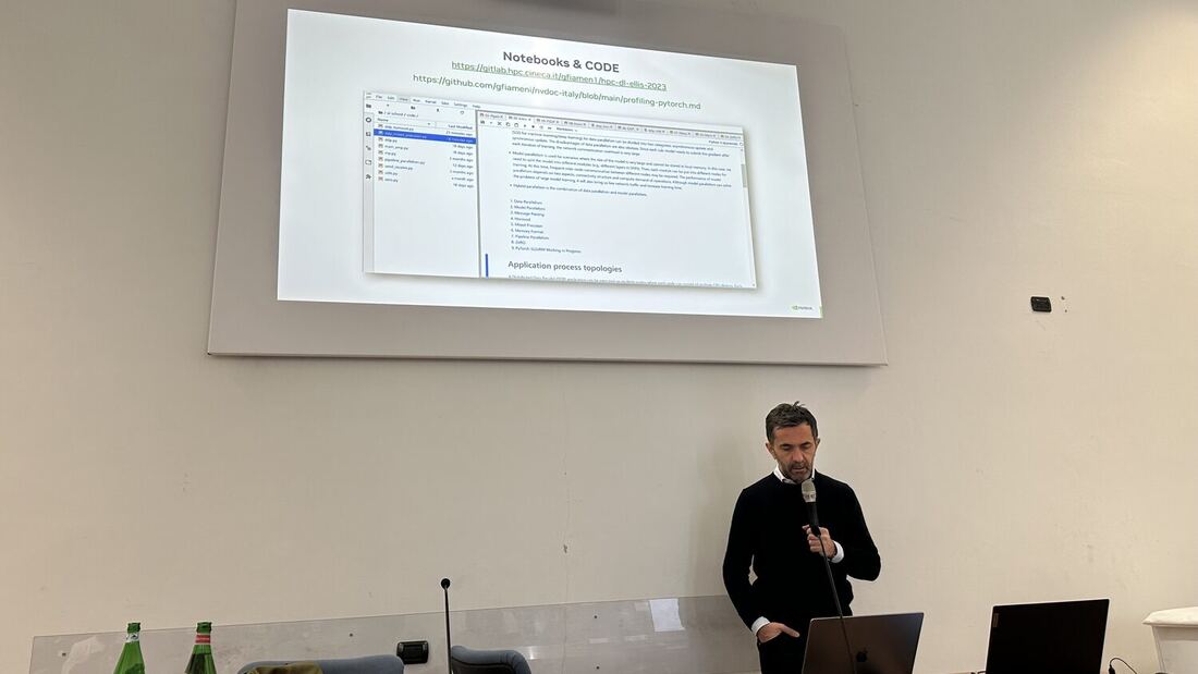 A speaker with a microphone stands under a slide headed Notebooks and CODE listing repository links for the practical session.
