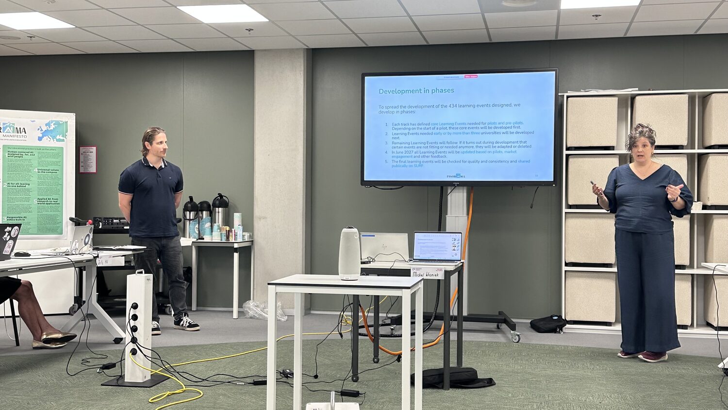 Two presenters flanking a slide headed Development in phases, setting out how the 434 designed learning events will be built.