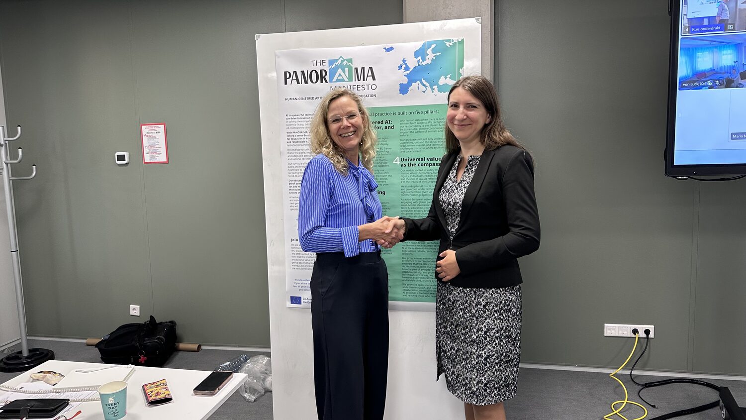 A handshake in front of the printed PANORAIMA Manifesto and its five pillars.