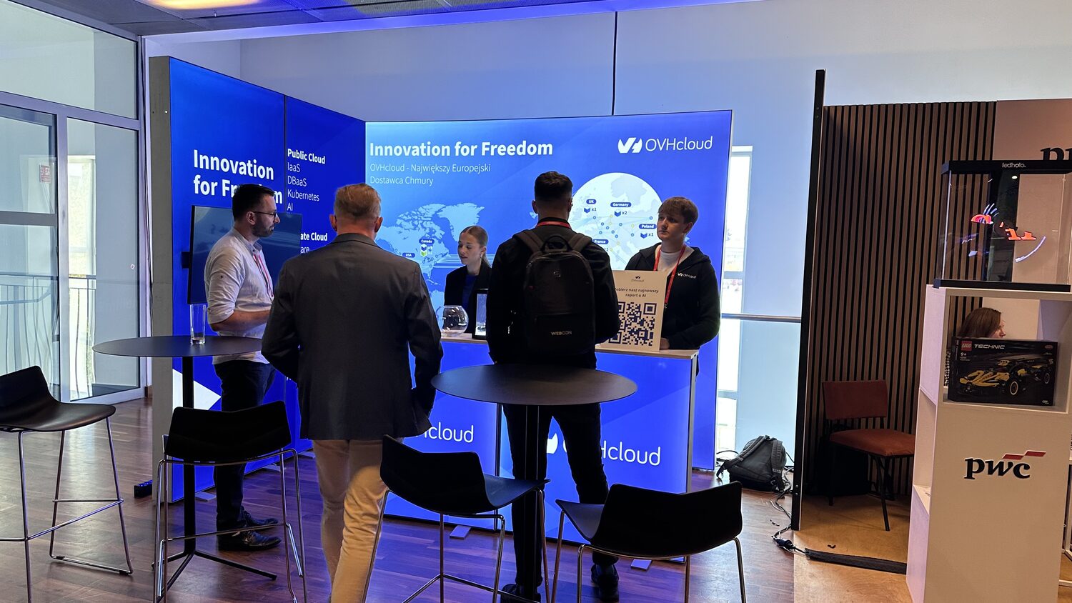The OVHcloud stand at AI Summit Poland, a lit blue wall reading Innovation for Freedom, with delegates in conversation at high tables.