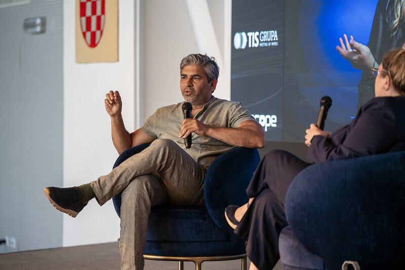 Tarry Singh seated in an armchair with a microphone during the fireside chat, the Croatian coat of arms on the wall behind.