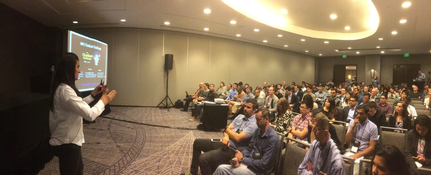 A full session room at the Machine Learning Innovation Summit in San Francisco, a speaker at the left of the stage and rows of seated attendees in lanyards.